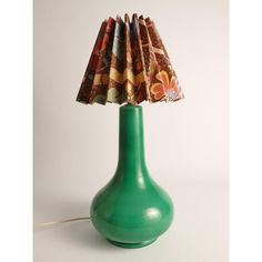 a green table lamp with a fabric shade on it's base and a white background