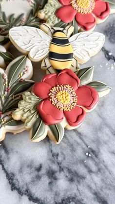 cookies decorated with flowers and bees on a marble surface