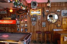 a pool table in a room with pictures on the wall and lights hanging from the ceiling