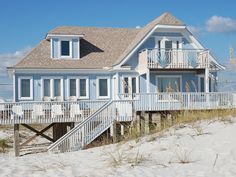 a house on the beach with stairs leading up to it's second floor and second story