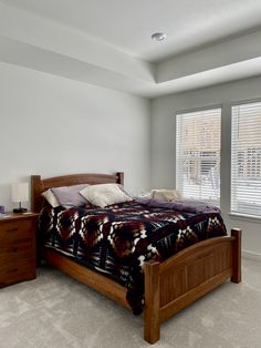 a bed sitting in a bedroom next to a window with blinds on the windowsill