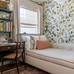 a living room with floral wallpaper and a white couch in front of a window