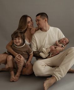 a man, woman and child are sitting on the floor with their arms around each other