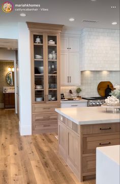 a large kitchen with white cabinets and wooden flooring on the walls, along with an island in the middle