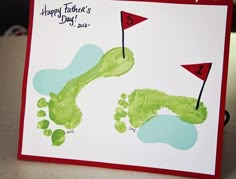 a handprinted card for father's day with green footprints and red flag