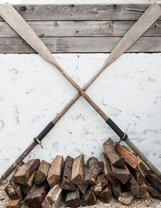 two baseball bats resting on top of firewood in front of a white brick wall