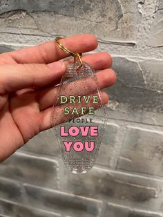 someone is holding up a clear keychain that says drive safe people love you