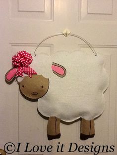 a sheep door hanger hanging from the side of a door with a pink bow on it's head