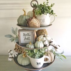 three tiered tray with white pumpkins, greenery and other fall decorations on it