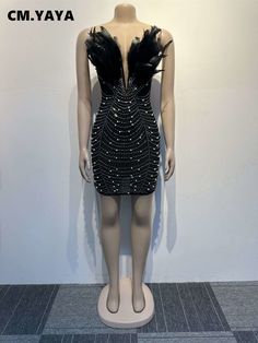 a mannequin wearing a black dress with feathers on it