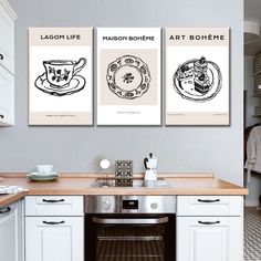 three posters on the wall above a stove in a kitchen with white cabinets and counters