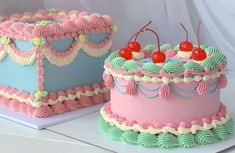 two cakes decorated in pastel colors with cherries on the top and one is pink