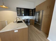 an empty kitchen with stainless steel appliances and wood cabinets