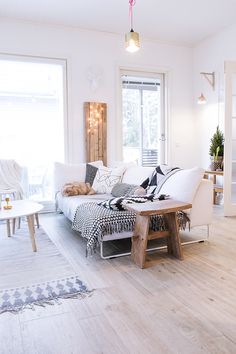 a living room filled with white furniture and lots of pillows on top of the couch