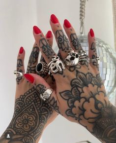 a woman's hands with tattoos and rings on them