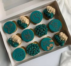 twelve decorated cupcakes in a box on a white tableclothed surface with the words happy new year written on them