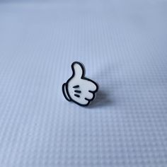 a black and white lapel pin with a thumbs up sign on it's side