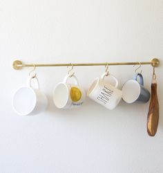 five coffee mugs hanging from a gold bar