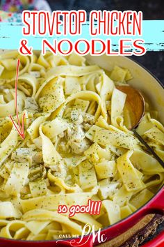 a red pot filled with pasta and chicken noodles next to a wooden spoon