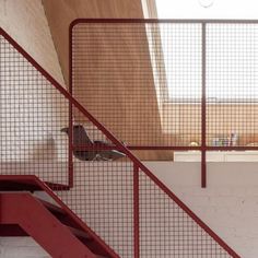 a bird sitting on top of a red railing next to a set of stairs