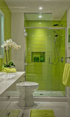 a bathroom with green tile and white fixtures, including a shower stall in the center