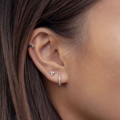 a close up of a woman's ear with two diamond studs on it