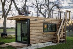 a small wooden cabin with stairs leading up to the roof and windows on top of it