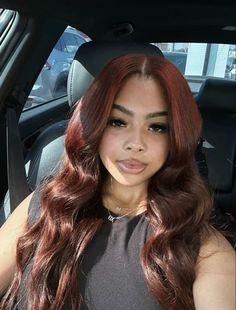 a woman sitting in the back seat of a car with long red hair and brown eyes