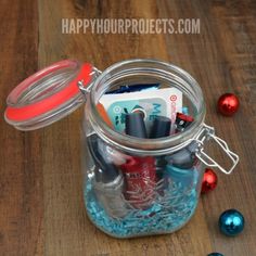 a jar filled with lots of different items on top of a wooden table next to christmas ornaments