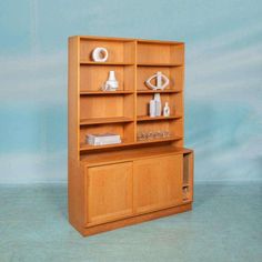 a wooden bookcase with several items on it and a blue wall in the background