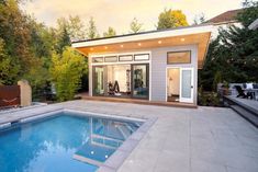 a small pool house with a large swimming pool in the middle and an outdoor gym