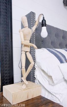 a wooden mannequin standing next to a lamp on a nightstand in a bedroom