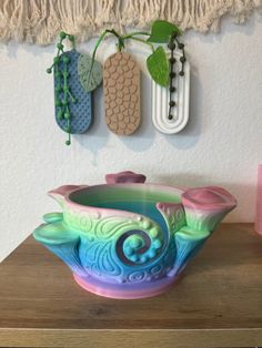 a bowl sitting on top of a wooden table next to two planters and hooks