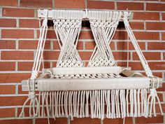 a white macrame hanging on a brick wall