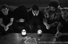 five people sitting around a table with candles and pentagrams on it in black and white