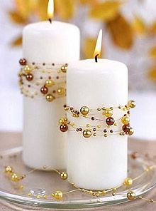 two white candles with gold beads on them