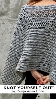 a woman wearing a gray crocheted shawl with the words knot yourself out written on it