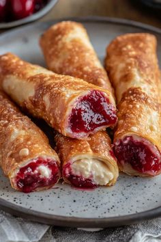 crepes with jelly filling on a plate next to some cherries in the background