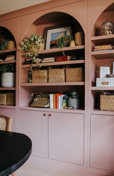 the shelves are filled with books and plants in baskets on top of them, along with wicker baskets