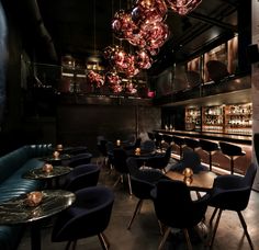 a dimly lit restaurant with blue velvet seating and chandeliers hanging from the ceiling