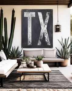 a living room filled with lots of plants next to a large painting on the wall