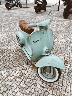 an old blue scooter is parked on the cobblestone street