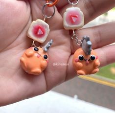 two small animal charms are being held in someone's hand