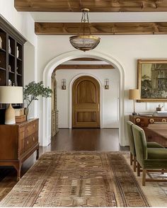 an archway leads into a formal dining room with wood flooring and wooden ceiling beams