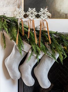 stockings hanging from a mantel decorated with greenery