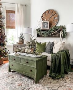 a living room decorated for christmas with green accents and decorations on the wall, along with a large clock