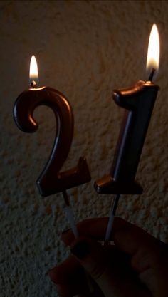 a person holding a lit candle with the number twenty on it