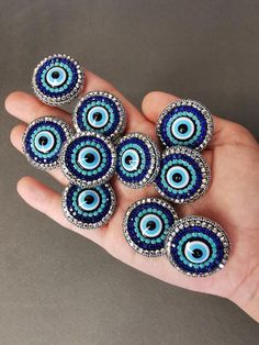 a hand holding five blue evil eye beads