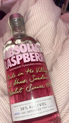 a bottle of absolut raspberry flavored vodka on top of a bed