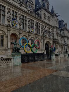 the olympic rings are on display in front of an old building with statues and flags